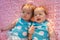 Sweet little twins lying on a pink blanket