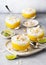 Sweet mango puree and cream cheese layered dessert decorated with roasted coconut chips and grated lime zest on glasses.