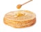 Sweet maple syrup dripping from dipper onto tasty thin pancakes