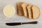 Sweet melted cheese in jar, pieces of bread, knife on table. Top view