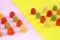 Sweet multi-colored candy marmalade in sugar sprinkles on a pink yellow background