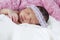 Sweet newborn girl wrapped in a pink and white blanket sleeping peacefully