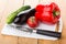 Sweet pepper, eggplant, cucumber, tomato, kitchen knife on cutting board