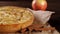 Sweet pie near cinnamon and apples on table