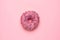 Sweet pink donut with multicolored sprinkles on a pink background flat lay