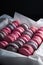 Sweet pink, violet french macaroon cookies in a box on black background