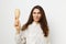 a sweet, pleasant, beautiful woman with well-groomed hair, standing on a light background holding a comb in her hands