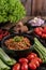 Sweet pork in a black bowl, complete with cucumbers, long beans, tomatoes, and side dishes