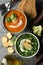 Sweet potato and broccoli cream soups on background, top view