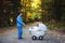 Sweet preschool boy pushing his little newborn baby boy, sleeping in old retro stroller in forest