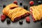 Sweet puff pastry with raspberries, blueberries, blackberries and cream cheese on black background.