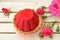 Sweet and red cake full of chocolate on pink roses background.Small cake near rose on wooden texture.