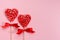 Sweet red lollipops hearts with ribbon on pastel pink as valentines day background.