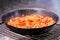 Sweet red pepper, tomato and onion are fried in a pan on the grill close-up for cooking lunch in nature. Selective focus