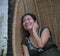 Sweet and relaxed Asian Chinese woman on her 20s wearing green Summer dress smiling happy and playful sitting at bamboo swing chai