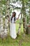 Sweet Russian girl girl in a white birch in the summer, with a wreath on her head and daisies