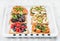 Sweet and savory breakfast toasts variety. Sandwiches with fruit, vegetables, eggs, smoked salmon on white baking tray