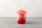 Sweet shaved ice or Spanish granizado in disposable plastic cup on grey background. Red Slushie - drink with natural juice.