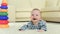 Sweet small baby playing with toys on a white carpet at home. Little baby boy with a toy lying on the floor at home.