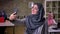Sweet smiling arab woman is taking selfies won her smartphone while standing indoor, brick light office, working girls