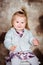 Sweet smiling little girl with blond hair sitting on chair