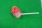 Sweet strawberry, very tasty, round sucking candy on a white plastic stick of white and pink color on a black background, chupik,