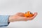 Sweet tangerine with funny face rests on palm, white background. Mandarin character