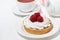 sweet tartlet with meringue and raspberry on white table