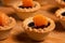 Sweet tartlets with chocolate and slices of tangerine on wooden dish for serving, close-up