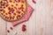 Sweet tasty pie with jellied and fresh raspberry fruits in baking dish with red tablecloth towel, wooden table background