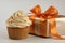 Sweet tasty vanilla cupcake whipped cream sprinkles topping pastry with wrapped festive Birthday present gift box orange