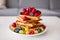 Sweet toddler birthday boy, eating belgian waffle with raspberries, blueberries, cocnut and chocolate