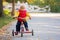 Sweet toddler boy, riding tricycle in the park on sunset, autumn