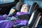 Sweet toddler girl sleeping peacefully in a car seat at winter season, warm clothing