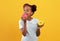 Sweet tooth afro-american girl eating donuts on yellow