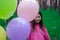 sweet tween brunette girl in pink holding colorful balloons outdoors. party, birthday concept. summertime. happy kids