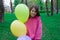 sweet tween brunette girl in pink holding colorful balloons outdoors. party, birthday concept. summertime. happy kids