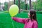 sweet tween brunette girl in pink holding yellow balloon outdoors