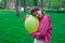 sweet tween brunette girl in pink holding yellow balloon outdoors