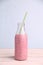 Sweet and yummy strawberry smoothie in the glass bottle with a straw