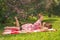 Sweetheart charming pinup girl in a summer dress on a checkered blanket in the Park near the bushes of lilac enjoys life and leisu