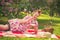 Sweetheart charming pinup girl in a summer dress on a checkered blanket in the Park near the bushes of lilac enjoys life and leisu