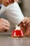 Sweets. Close Up Of Hands Decorating Dessert On Table