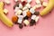 Sweets on pink background with copy space. Delicious chocolates candies, homemade marshmallow zephyr, banana and