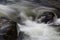 Swiftly flowing water across large rocks in a fall landscape