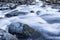 Swiftly moving river water over and around large rocks winter landscape