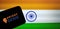 Swiggy Genie logo on a smartphone with blurred Indian flag background