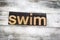 Swim Letterpress Word on Wooden Background