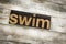 Swim Letterpress Word on Wooden Background