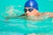 Swimmer in blue cap and goggles swimming in pool